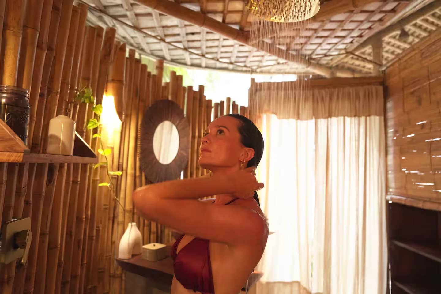 A guest under the rainfall shower in the semi-open bamboo bathroom at Mauna Tulum